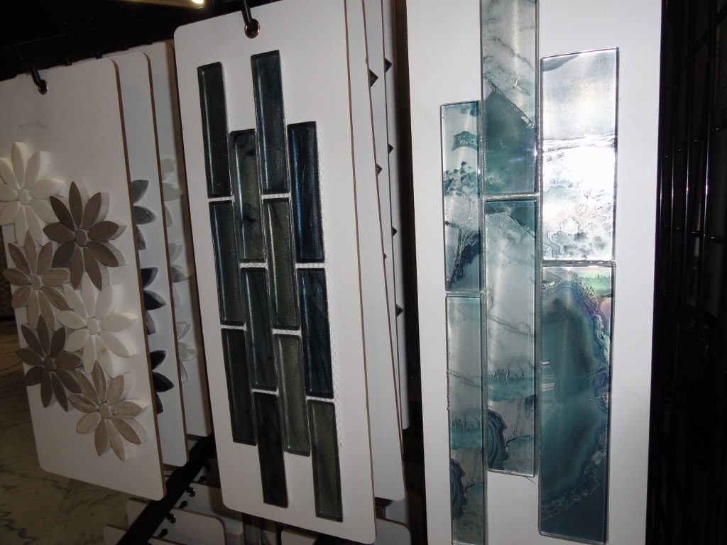 Floral mosaic and glass tile sample cards on showroom rack